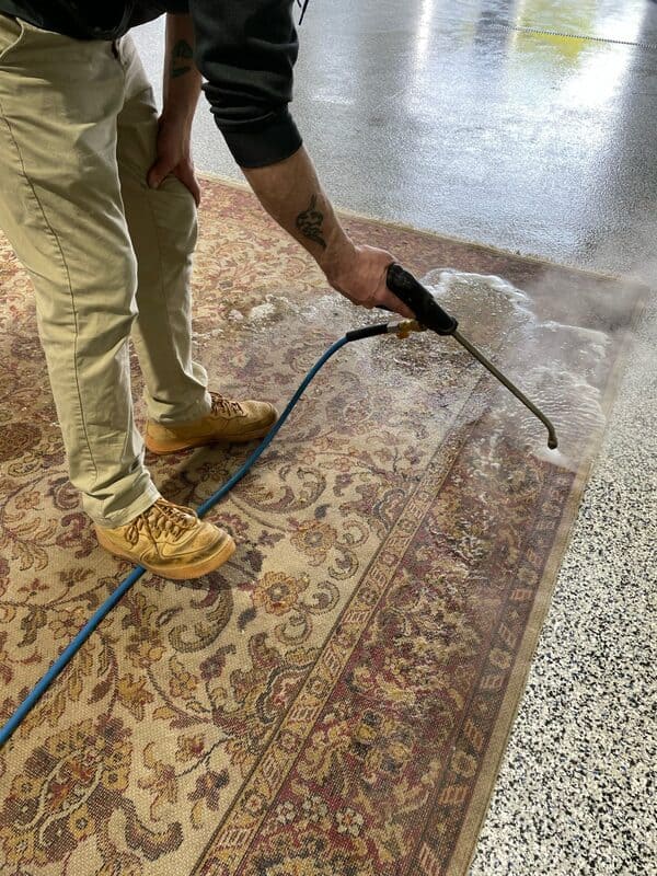 Worker at Pro-Master Cleaning & Restoration power washing a rug