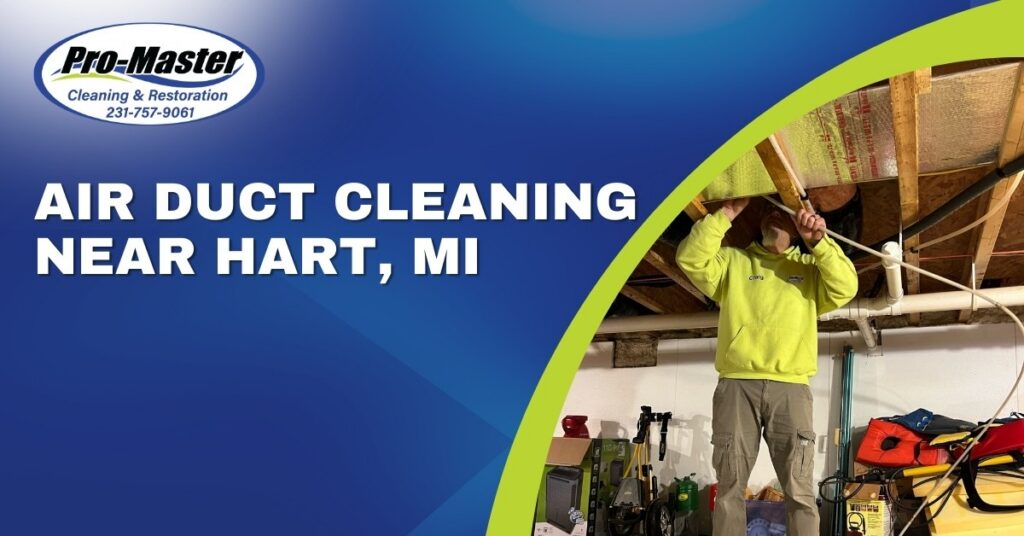 Promotional graphic for Pro-Master Cleaning & Restoration, advertising air duct cleaning services near Hart, MI. The left side features a blue background with the company logo, phone number (231-757-9061), and bold white text reading 'AIR DUCT CLEANING NEAR HART, MI.' The right side shows a photo of a man in a lime green hoodie with 'Craig' on the chest, inspecting or working on air ducts in a basement or crawl space. The background includes wooden joists, pipes, and various tools and equipment, such as a red vacuum, a yellow machine with a hose, and life vests. A thick, curved lime green line separates the text and photo, adding a dynamic visual element.
